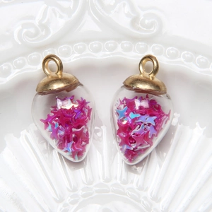Close-up of heart-shaped glass pendants with pink and blue star sequins on ceramic plate