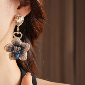 Gros plan détaillé des boucles d'oreilles vintage asymétriques avec fleurs brodées bleues