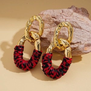 Detail of metallic golden irregular loop earrings with red and black woven texture rings