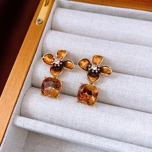 Detailed macro view of vintage gold-plated floral earrings with amber stones in a jewelry box