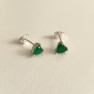 Macro view of heart-shaped green zircon studs with silver four-prong setting and butterfly back