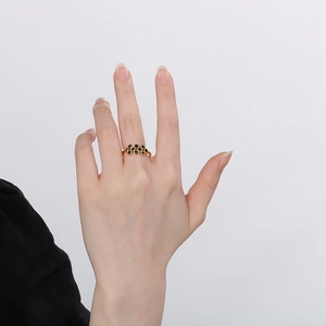 Close-up of a gold pearl open ring with black gemstone cluster on a model hand