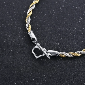 Bicolore gedrehte Kettenarmband mit Herz-Knebelverschluss auf dunklem Hintergrund