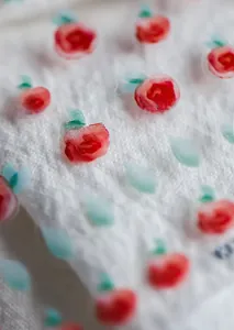 Macro detail of ultra-thin red rose floral nail art stickers on textured fabric