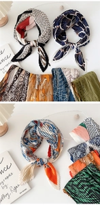 Flat lay detail showing various pleated silk scarves with diverse colorful abstract patterns