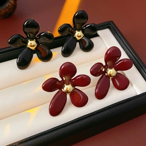 Close-up of black and deep red floral earrings with golden pistils in jewelry box
