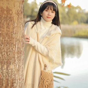 Bohemian off-white knit poncho with decorative tassels and a buttoned hooded neckline