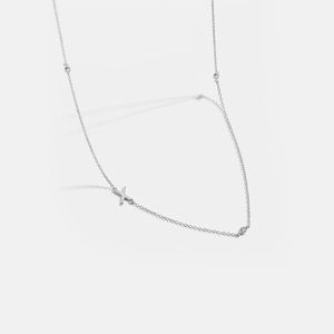 Macro detail of silver-plated X-pendant necklace with four sparkling round accents