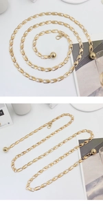 Detail of adjustable gold metal waist chain belt with spherical pendant and lobster clasp