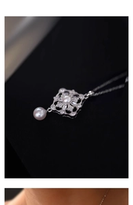 Macro shot of elegant water drop pearl pendant with cubic zirconia flower on black velvet