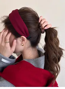 Detail view of a burgundy fabric headband with a matte finish and hand-made label