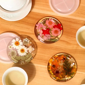 Detail of round epoxy resin coasters with embedded dried flowers on wood table