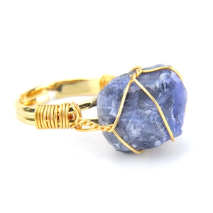 Detail of handcrafted gold wire wrapping on a natural blue raw agate gemstone ring