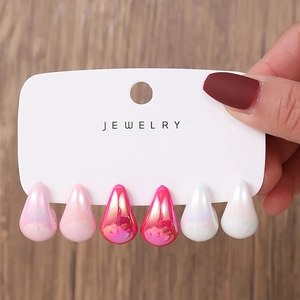 Detailed close-up of 3 pairs of teardrop-shaped acrylic earrings with iridescent finish