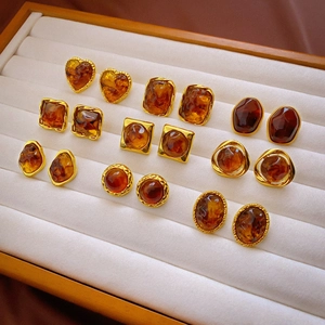 Detail of amber resin stud earring set with irregular geometric shapes and gold metal frames