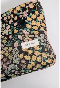 Detail of floral jacquard texture and H&R BAG logo on this portable cosmetic organizer