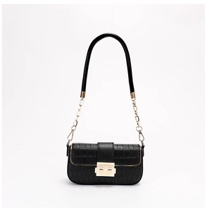 Close-up of black crocodile texture with golden metal chain and secure latch lock