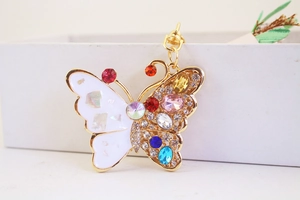 Close-up of golden butterfly keychain with colorful rhinestones and white enamel detail