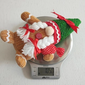 Detail shot showing a 105g Christmas gingerbread gnome plush toy on a kitchen scale