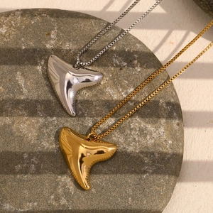 Detailed shot of stingray pendant necklaces in gold and silver on stone plate