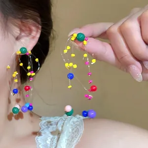 Macro shot of colorful beaded tassel earrings with multi-layered resin beads on a model