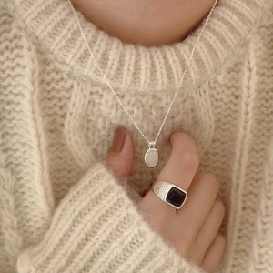 Close-up of minimalist silver 925 necklace with white stone and black square ring