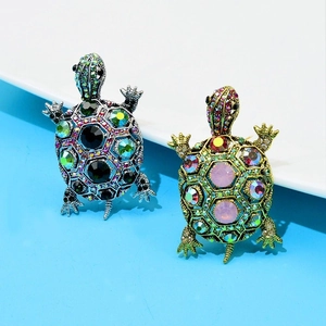 Close-up of vintage turtle brooches with silver and gold bases featuring colorful rhinestones