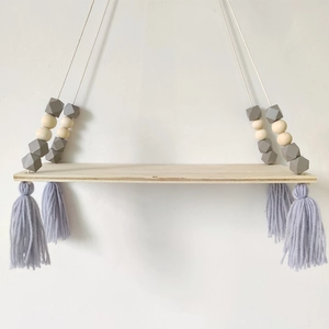 Detail of Nordic wooden hanging shelf with grey tassels and octagonal macaron beads