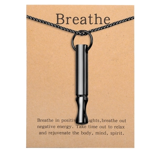 Close-up of black meditation whistle necklace on kraft card with mindfulness text