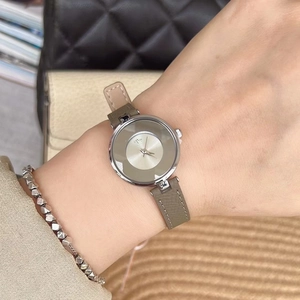 Detail view of a minimalist round silver watch with taupe leather strap on wrist