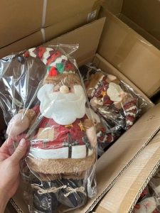 Close-up of plush Santa Claus doll in packaging showing striped hat and berry detail