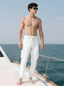 Men's white cargo pants with drawstring waist and pockets on a yacht deck
