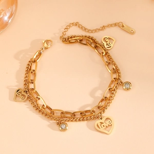 Dettaglio di un bracciale dorato a doppio strato con ciondoli a cuore e piccoli cristalli
