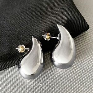 Macro view of polished silver teardrop earrings with organic curved design