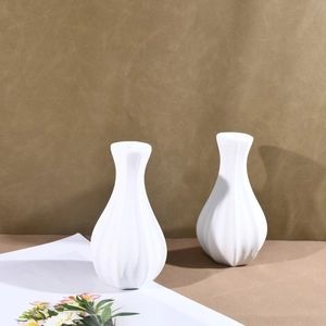 Detailed macro view of white ceramic vases featuring elegant vertical ribbed texture