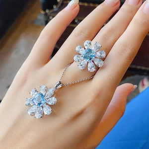 Detail view of blue topaz floral jewelry set with silver necklace and ring on model