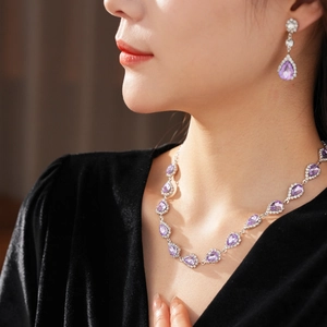 Close-up of vintage jewelry set with purple waterdrop gems and cubic zirconia on model