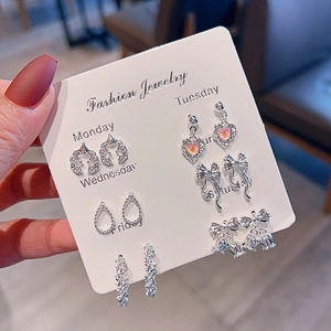 Detail of silver stud earrings set featuring pink hearts and butterfly designs on card