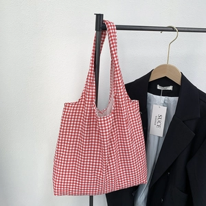 Detail of red and white gingham canvas tote bag hanging next to a black blazer