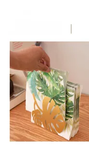 Vertical gold metal napkin holder with creative monstera leaf design for home and dining use