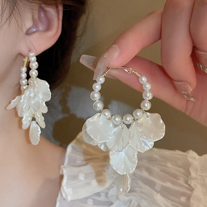 Detail of elegant pearl hoop earrings with layered white petal tassels and gold finish