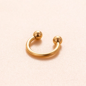 Macro shot of a golden titanium circular barbell for septum and cartilage piercing