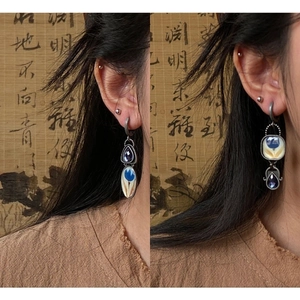 Detail view of vintage Egyptian enamel earrings with blue drop gemstones and floral patterns