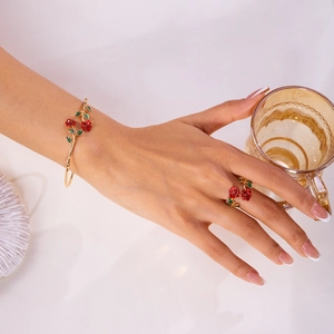 Detail of red enamel rose open bracelet and ring set with gold-plated finish on a model