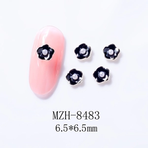 Macro shot of 6.5mm black 3D camellia nail charms with white pearls on silver alloy base