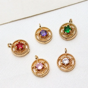 Macro shot of colorful 6mm round crystal glass charms with golden edges and dual loops
