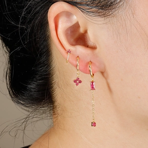 Golden earrings set with deep red gemstones and chain tassels on female model