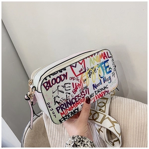 Close-up of white graffiti camera bag featuring textured leather and wide patterned strap