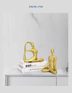 Detail view of two gold abstract yoga figures in stretching poses on a modern shelf