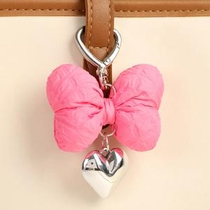 Detail of pink bow keychain with silver heart pendant and metal spring hook on leather strap